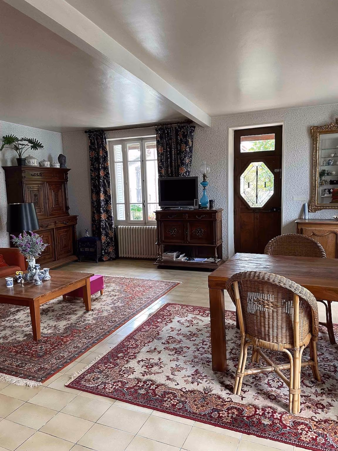 Woonkamer met houten kast, spiegel boven de schoorsteenmantel en een dressoir met kleine ornamenten